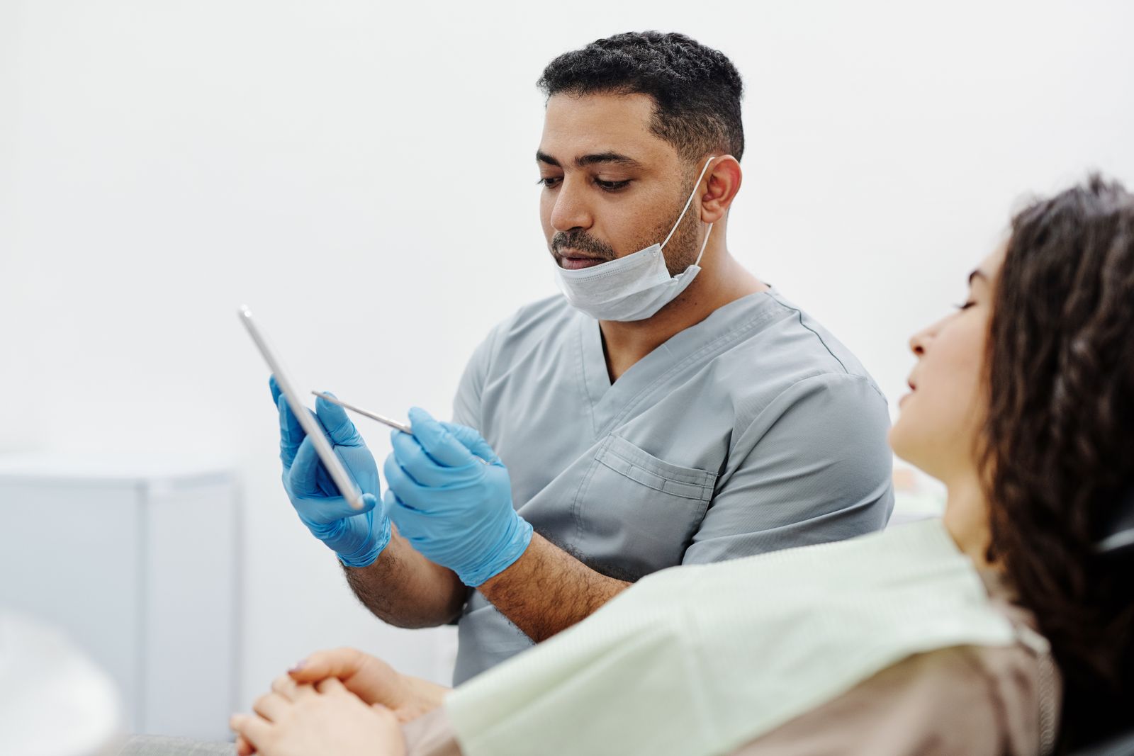 Dentist at Burnaby South Dental in Highgate, Burnaby showing a patient dental crown options on a tablet